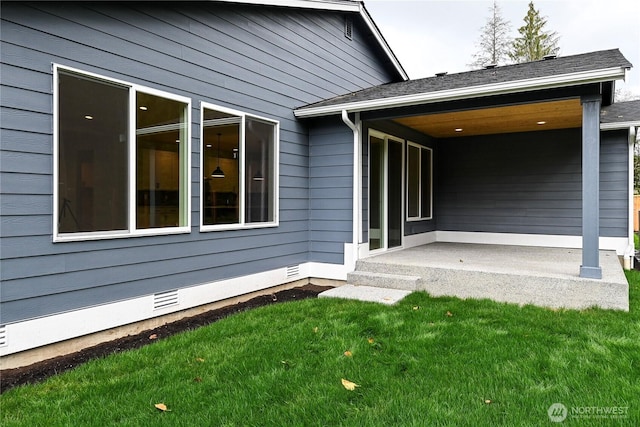 view of exterior entry with crawl space, a shingled roof, and a yard