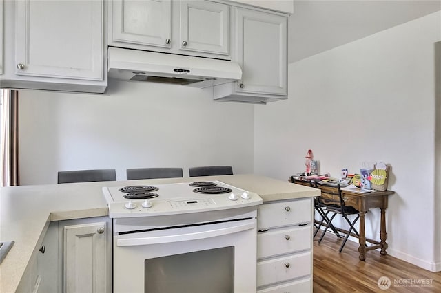 kitchen with white electric stove, light wood-style flooring, under cabinet range hood, baseboards, and light countertops