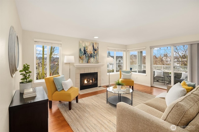 living room featuring recessed lighting, a fireplace, baseboards, and wood finished floors