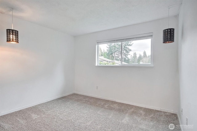 carpeted spare room featuring a textured ceiling and baseboards