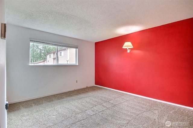 carpeted empty room with a textured ceiling and baseboards