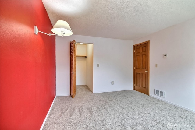 unfurnished bedroom with light colored carpet, a closet, visible vents, and a textured ceiling