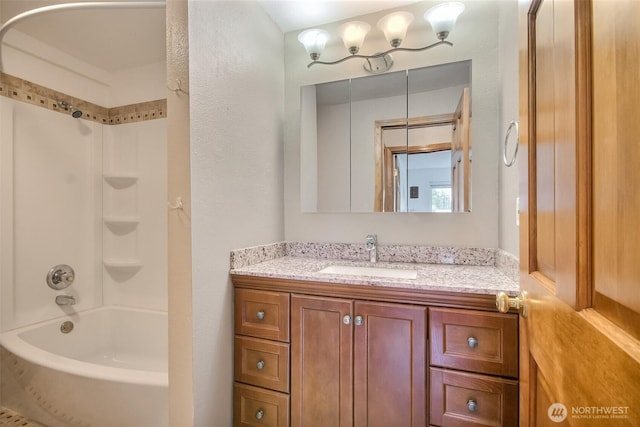 bathroom with a textured wall, shower / bathing tub combination, and vanity