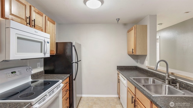 kitchen featuring dark countertops, white appliances, a sink, and baseboards