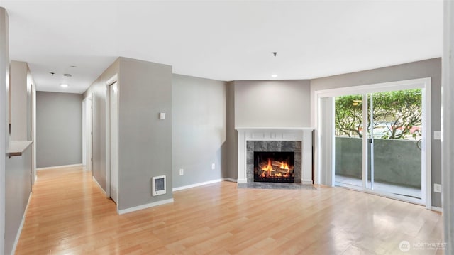 unfurnished living room with visible vents, baseboards, a high end fireplace, light wood-style flooring, and recessed lighting