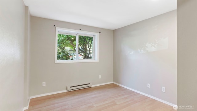 unfurnished room featuring a baseboard heating unit, baseboards, and wood finished floors