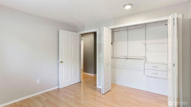 unfurnished bedroom with light wood-style flooring, baseboards, and a closet