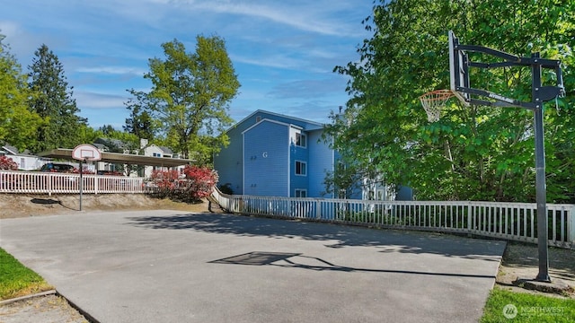 view of sport court featuring basketball hoop and fence