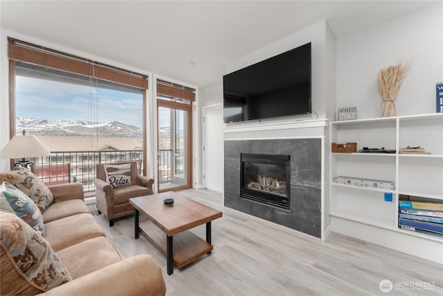 living area featuring expansive windows, a tiled fireplace, and wood finished floors