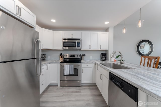 kitchen featuring recessed lighting, a sink, white cabinetry, appliances with stainless steel finishes, and light wood finished floors