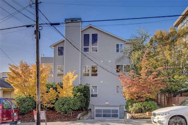 view of home's exterior featuring an attached garage, a chimney, and fence