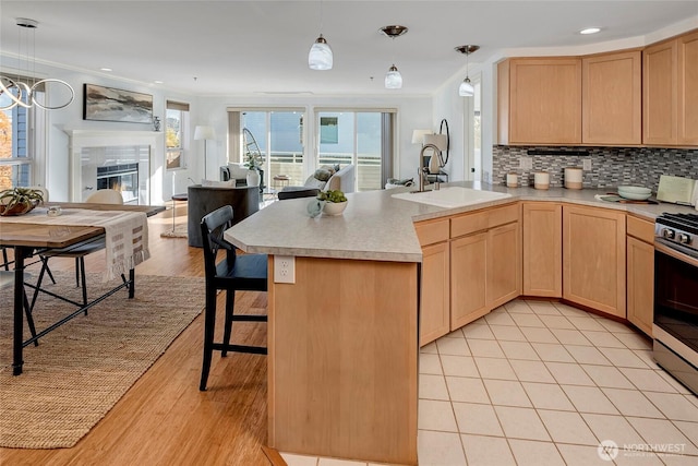 kitchen with tasteful backsplash, open floor plan, light brown cabinets, and a sink