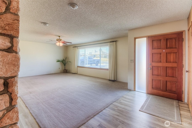 foyer with carpet, a textured ceiling, a ceiling fan, and wood finished floors