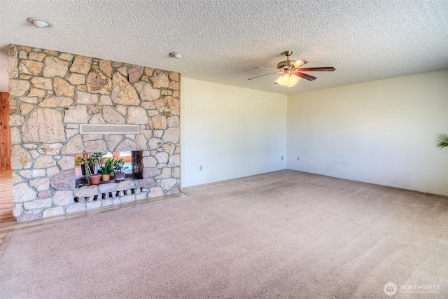 unfurnished living room featuring a ceiling fan, carpet, a fireplace, and a textured ceiling