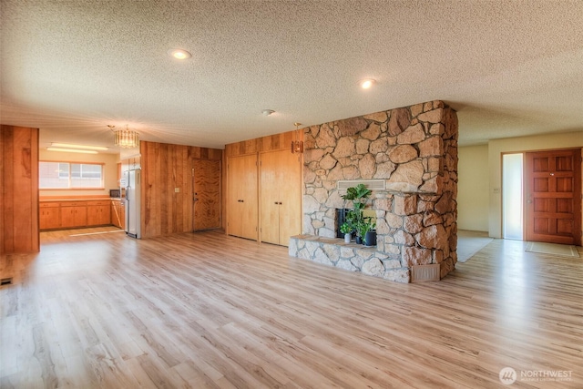 unfurnished living room with light wood-type flooring, a fireplace, and a textured ceiling