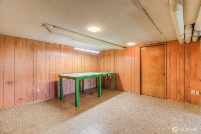 game room with a textured ceiling, wooden walls, and tile patterned floors