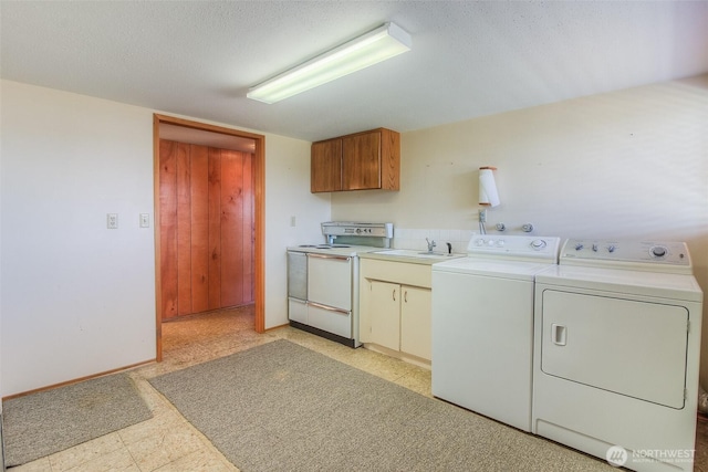 laundry area featuring baseboards, independent washer and dryer, a textured ceiling, light floors, and a sink