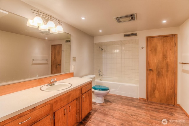 full bath featuring toilet, visible vents, wood finished floors, and vanity