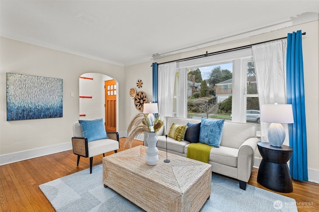 sitting room featuring arched walkways, baseboards, and wood finished floors