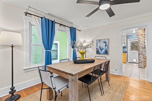 dining space featuring light wood-style floors, a healthy amount of sunlight, baseboards, and a ceiling fan