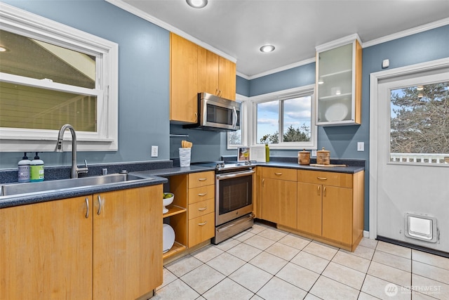 kitchen with light tile patterned floors, stainless steel appliances, dark countertops, ornamental molding, and a sink