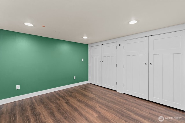 unfurnished bedroom featuring recessed lighting, dark wood-style flooring, baseboards, and two closets