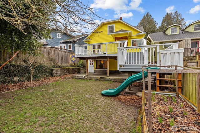 view of playground featuring a deck, a patio, a lawn, and a fenced backyard