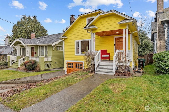 bungalow-style home with a front lawn, a chimney, and an attached garage