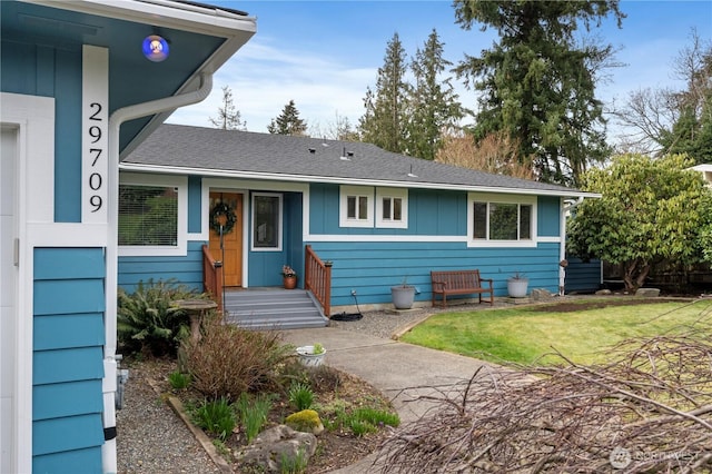 view of front of house featuring board and batten siding, a front yard, and a shingled roof