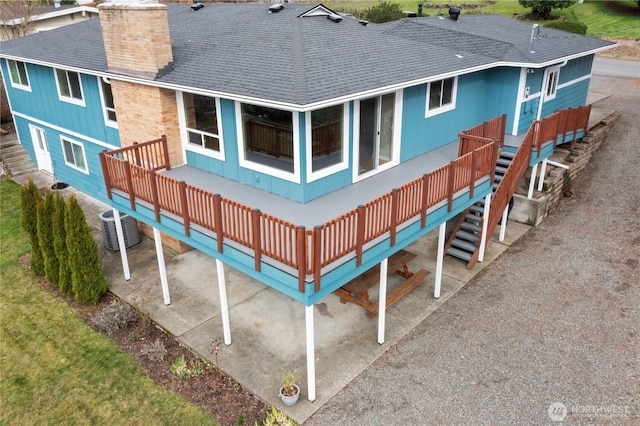 back of property featuring stairs, cooling unit, and roof with shingles