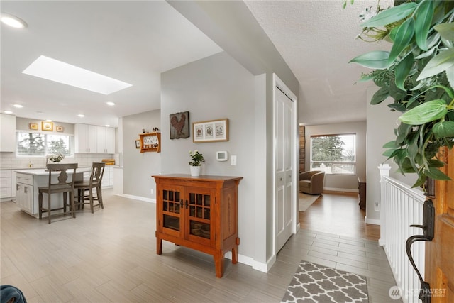 entrance foyer with a skylight, light wood-style floors, and baseboards