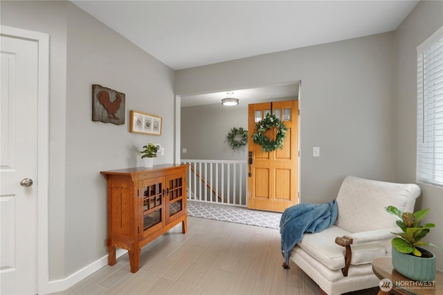 living area with baseboards, an upstairs landing, and light wood finished floors