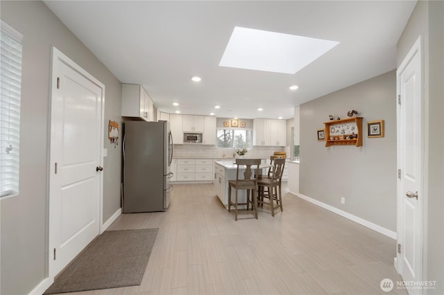 kitchen featuring tasteful backsplash, a center island, a breakfast bar area, white cabinets, and stainless steel appliances