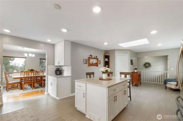 kitchen featuring visible vents, light wood-style flooring, white cabinetry, and a skylight