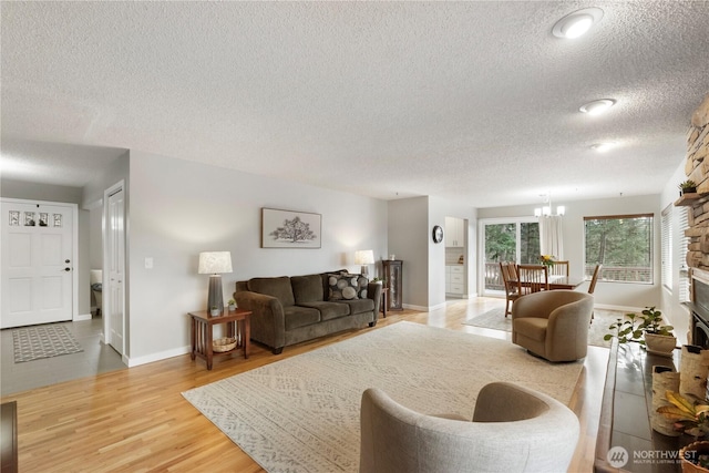 living area with a notable chandelier, wood finished floors, baseboards, and a textured ceiling