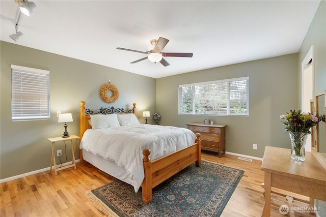 bedroom with light wood-style flooring, visible vents, baseboards, and ceiling fan