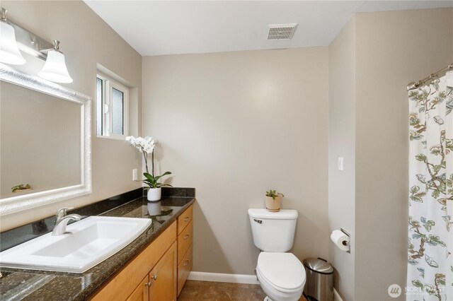 bathroom with vanity, baseboards, visible vents, tile patterned floors, and toilet