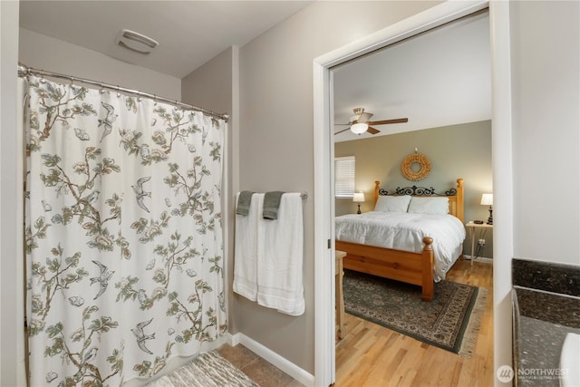 ensuite bathroom with baseboards, ensuite bathroom, a shower with curtain, wood finished floors, and a ceiling fan