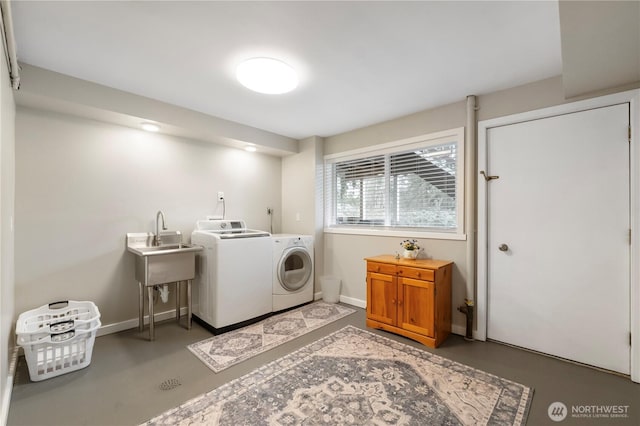 washroom with a sink, baseboards, laundry area, and washing machine and clothes dryer