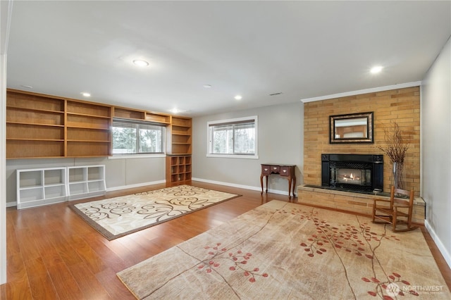 living area with a brick fireplace, recessed lighting, wood finished floors, and baseboards