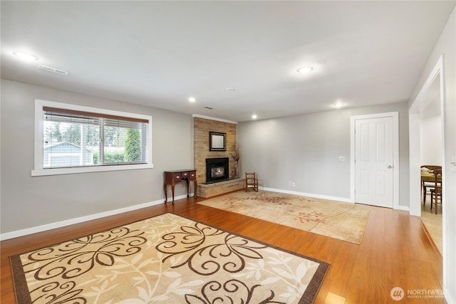 living room featuring light wood finished floors, visible vents, a brick fireplace, baseboards, and recessed lighting