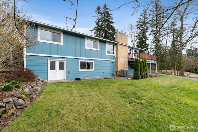 back of property featuring central air condition unit, a yard, board and batten siding, and a chimney