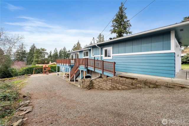 view of front facade with a deck, stairs, and gravel driveway