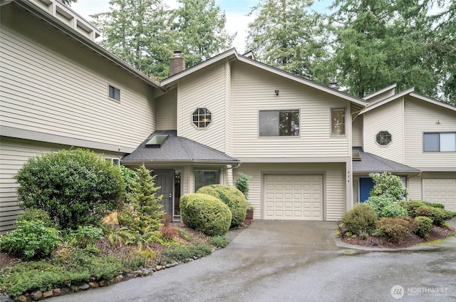 view of property featuring a garage, driveway, and a chimney