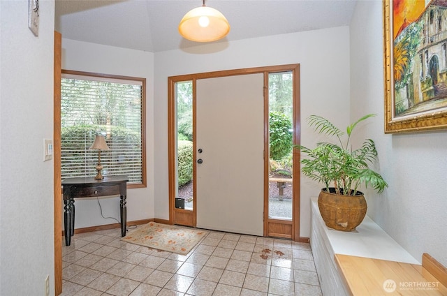 foyer entrance featuring light tile patterned floors, plenty of natural light, and baseboards