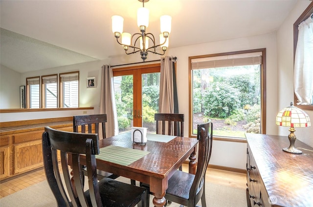 dining area featuring french doors, light wood-style flooring, baseboards, and an inviting chandelier