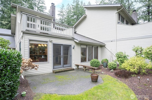 rear view of house featuring a patio, a chimney, and a balcony