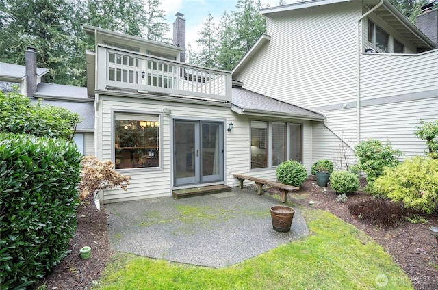 rear view of property featuring a patio, french doors, a chimney, and a balcony