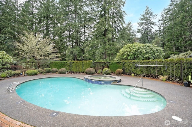 view of swimming pool with a pool with connected hot tub, a patio area, and fence