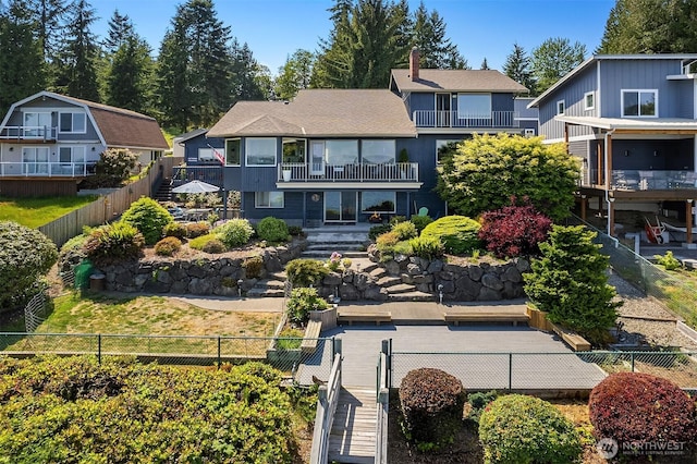 back of property featuring a balcony, a fenced front yard, and a residential view